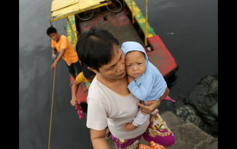 Una mujer atraviesa un río con su bebé en brazos, en una aldea costera en Las Pinas, sur de Manila; durante una evacuación. EFE /