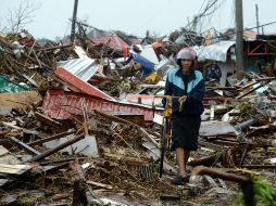 Un hombre camina sobre los escombros de varias casas en la región de Tacloban. AFP /