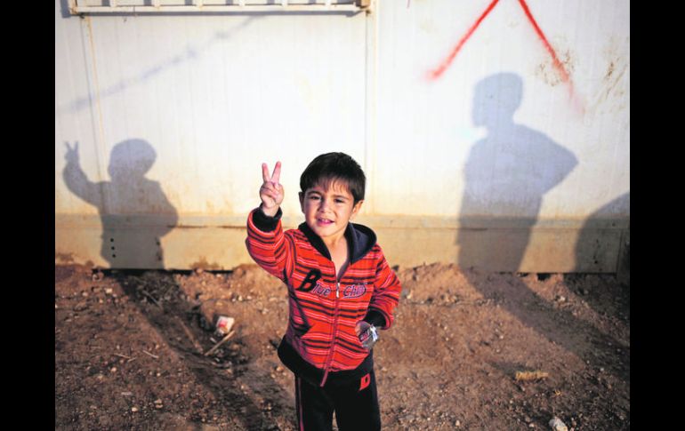 Rayyan Nasser de cuatro años hace la señal de la victoria frente a su familia, al establecerse en un campamento de refugiados AP /