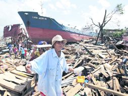 Una sobreviviente del tifón 'Haiyan' en la ciudad de Tacloban camina sobre los escombros que dejó el meteoro que azotó Filipinas. AP /