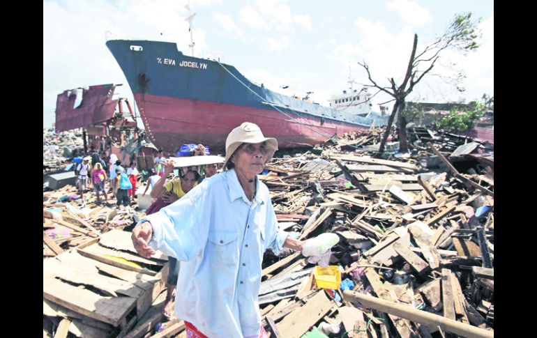 Una sobreviviente del tifón 'Haiyan' en la ciudad de Tacloban camina sobre los escombros que dejó el meteoro que azotó Filipinas. AP /