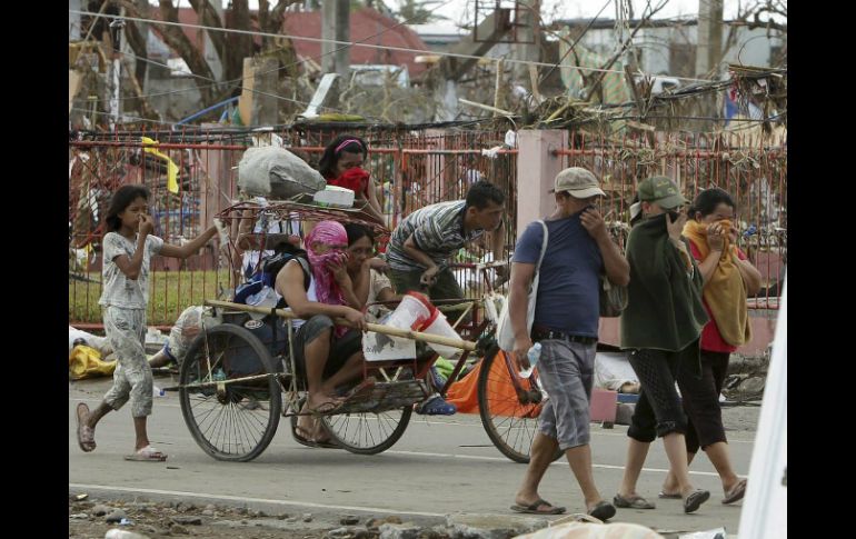 Una familia se tapa la nariz al pasar cerca de las víctimas del paso de 'Haiyán'. EFE /