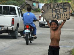 Un niño pide ayuda a los automovilistas en una zona devastada de la localidad de Borbon. ARCHIVO /