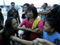 Varios supervivientes se agarran a sus familiares mientras son obligados a subirse a un avión militar que los trasladará a Manila. EFE /