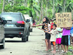 Varios niños piden ayuda a los ocupantes de los coches que circulan en una zona devastada por el paso tifón ''Haiyan''. EFE /