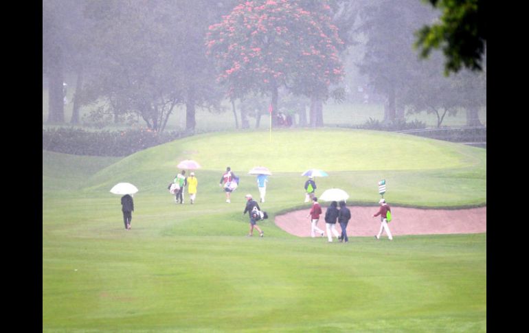 Uno de los grupos llega al green del hoyo 1 bajo la lluvia.  /