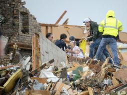 Equipos de rescate ayudan a un residente herido en Illinois por el tornado. AP /