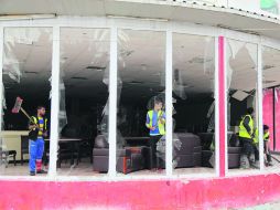 Iraquíes limpian los escombros de una tienda tras de un atentado con un coche-bomba, en el barrio de Karrada en el centro de Bagdad. AP /