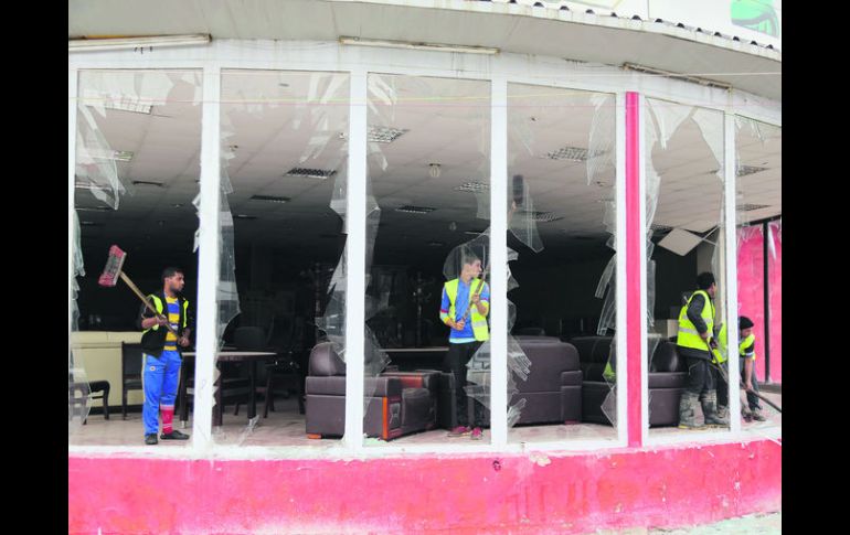 Iraquíes limpian los escombros de una tienda tras de un atentado con un coche-bomba, en el barrio de Karrada en el centro de Bagdad. AP /