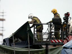 Bomberos observan la parte expuesta de la cola del helicóptero sobre el pub Clutha. AP /