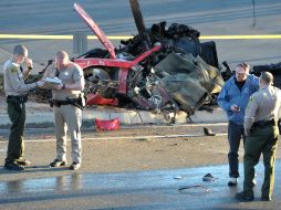 Agentes realizan el peritaje en la zona del accidente, detrás la imagen del auto. AP /