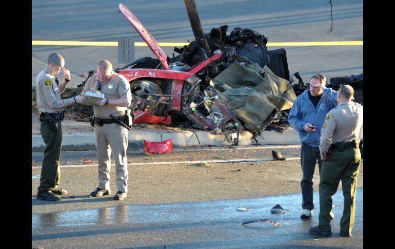 Agentes realizan el peritaje en la zona del accidente, detrás la imagen del auto. AP /