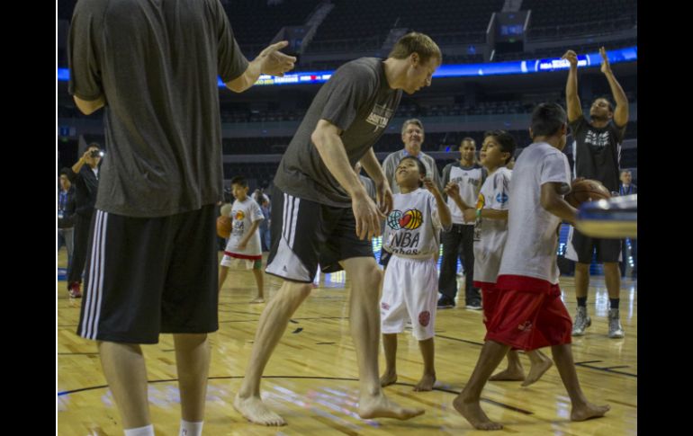 Jugadores de Spurs juegan con los pequeñines indígenas. AP /