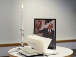 Un retrato de Nelson Mandela , junto a una vela encendida y un libro de condolencias. El mundo se conduele. AFP /