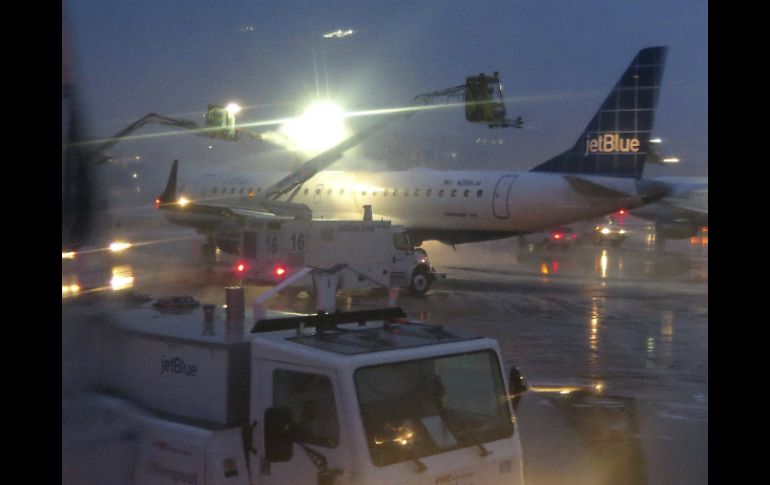 Operarios utilizan sopletes para derretir el hielo del fuselaje de un avión. EFE /