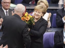 Merkel, recibe un ramo de flores y el aplauso de la Cámara Baja tras ganar los votos para su investidura en el Parlamento en Berlín. EFE /