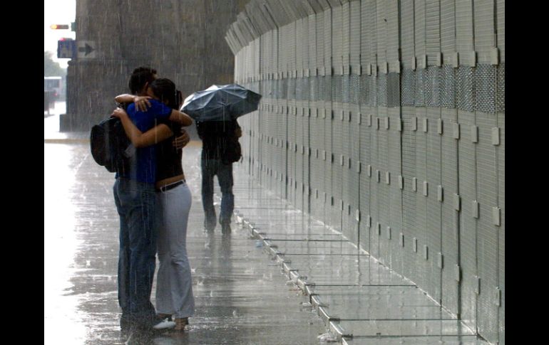 Una pareja se abraza bajo la lluvia. ARCHIVO /