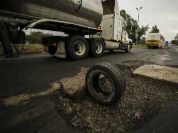 Un camión pasa cerca de un bache, marcado por una llanta en Lázaro Cárdenas.  /