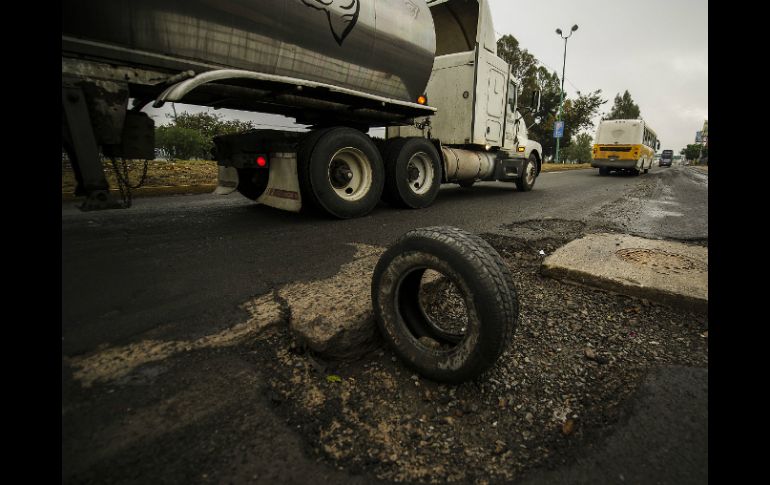 Un camión pasa cerca de un bache, marcado por una llanta en Lázaro Cárdenas.  /