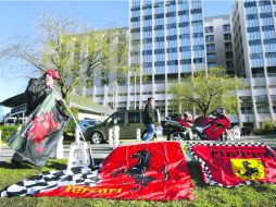 Un aficionado con banderas de Ferrari se postra a las afueras del hospital donde permanece en coma el siete veces campeón de la F1. AFP /