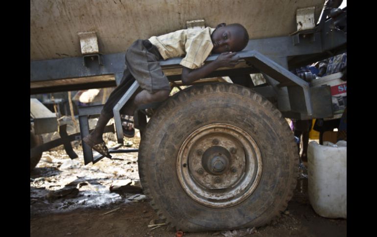 Un niño desplazado descansa en una llanta de una camión contenedor de agua, cientos de personas han perdido sus hogares. ARCHIVO /