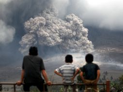 Tres personas miran una de las erupciones del Sinabung, situado en el norte de la isla de Sumatra. AP /