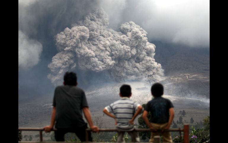 Tres personas miran una de las erupciones del Sinabung, situado en el norte de la isla de Sumatra. AP /