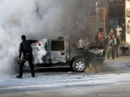 Un policía intenta extinguir un vehículo de la policía incendiado por simpatizantes de la Hermandad Musulmana durante las protestas de AFP /