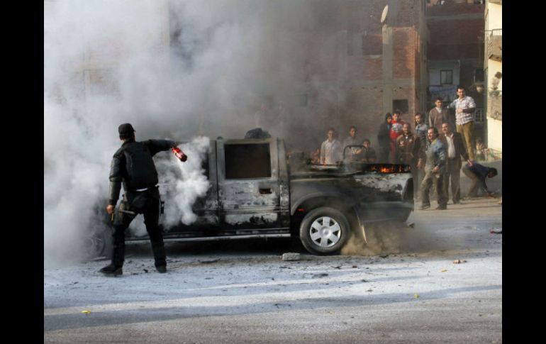 Un policía intenta extinguir un vehículo de la policía incendiado por simpatizantes de la Hermandad Musulmana durante las protestas de AFP /