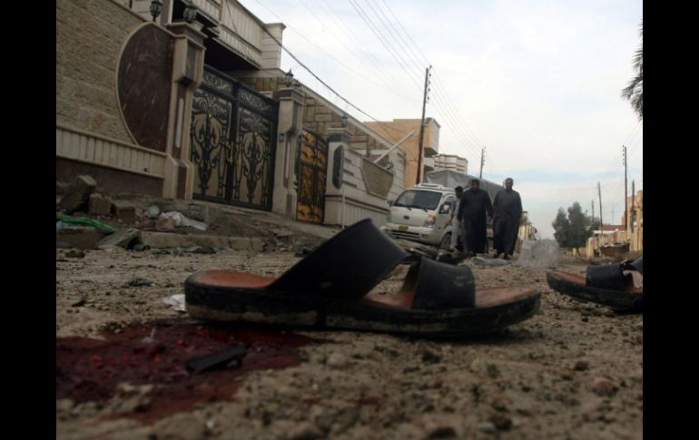 Un grupo de hombres camina por el lugar donde dos civiles murieron y otros cuatro resultaron heridos por el impacto de proyectiles. EFE /