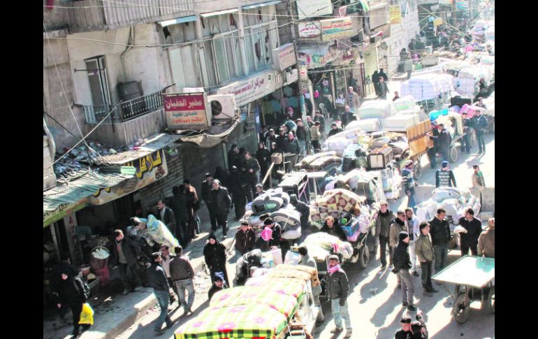 Cientos de sirios se concentran con sus pertenencias en el distrito de Bustan al-Qasr, en la ciudad de Alepo. AFP /