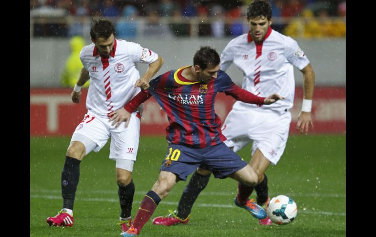 El delantero del FC Barcelona Lionel Messi (c) disputa un balón con el defensa del Sevilla Nicolás Pareja (i). EFE /