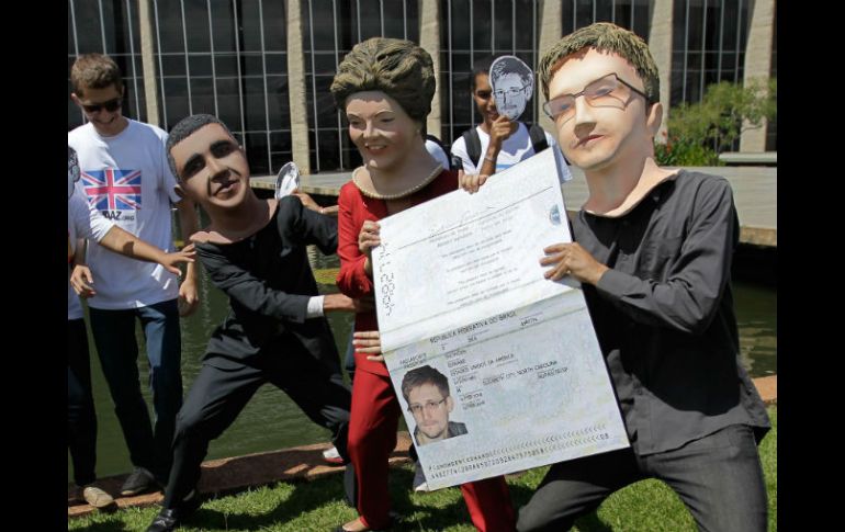 Artistas disfrazados representan una escena cómica en la que Rousseff da a Snowden un pasaporte brasileño y Obama trata de evitarlo. AP /