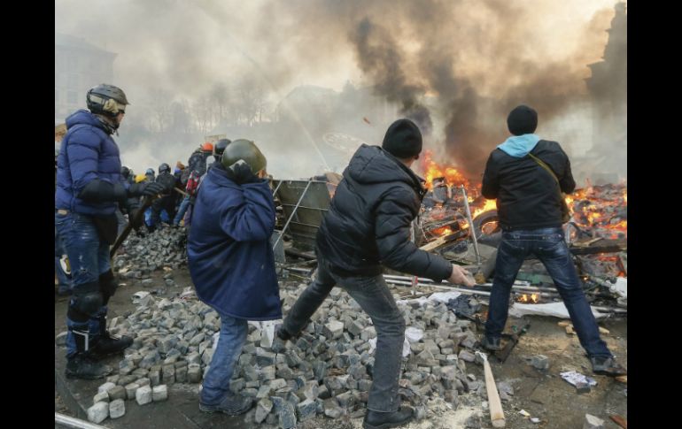 Manifestantes lanzan piedras contra los agentes antidisturbios durante las protestas violentas en el centro de Kiev, Ucrania. EFE /