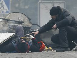 Un hombre trata de ayudar a un manifestante que resulta herido durante los disturbios entre opositores y policía, en Kiev. EFE /