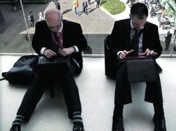 Dos ejecutivos trabajan con sus laptops en el suelo de una de las pasarelas en el Mobile World Congress. EFE /