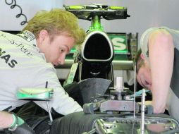 Nico Rosberg y un mecánico del equipo Mercedes hacen modificaciones al monoplaza, previo a la práctica uno del GP de Australia. AFP /