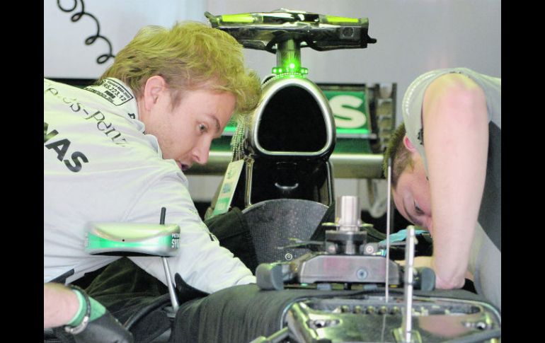 Nico Rosberg y un mecánico del equipo Mercedes hacen modificaciones al monoplaza, previo a la práctica uno del GP de Australia. AFP /