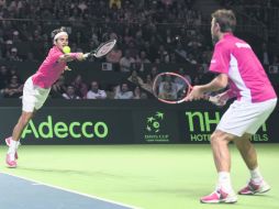 Roger Federer se estira para tratar de regresar una bola durante el juego de dobles. AFP /