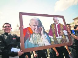 Dos sacerdotes sostienen una imagen con los dos próximos santos junto a la Basílica de San Pedro en El Vaticano. EFE /