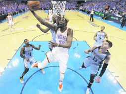 Kevin Durant penetra para disparar a la canasta, ante la marcación de tres elementos de Memphis. AP /