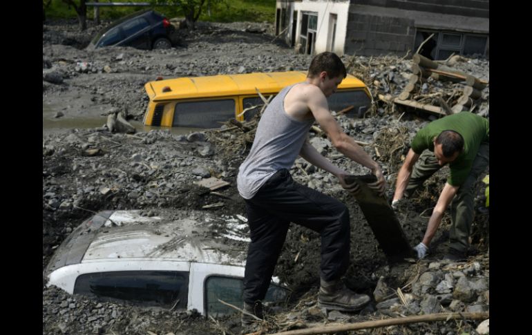 Ciudadanos de Bosnia buscan excavar su automóvil enterrado entre el lodo producido por las inundaciones. AP /