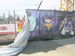 Un trabajador coloca una manta de los Vikingos para cubrir la zona de trabajos donde será el nuevo estadio del equipo. AP /