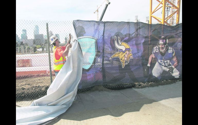 Un trabajador coloca una manta de los Vikingos para cubrir la zona de trabajos donde será el nuevo estadio del equipo. AP /