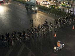 Un motociclista pasa frente al bloqueo preventivo de los soldados en Tailandia. AP /