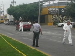 Agentes de la Fiscalía General del Estado y del Instituto Jalisciense de Ciencias Forenses realizan el levantamiento del cadáver.  /