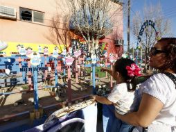 Familiares y amigos rezan y lloran frente a las fotografías de sus hijos colocadas frente a la fachada de la guardería.  /