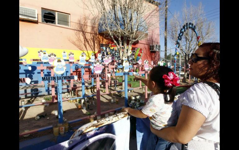 Familiares y amigos rezan y lloran frente a las fotografías de sus hijos colocadas frente a la fachada de la guardería.  /