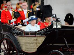 La monarca luce un vestido azul y sombrero, mientras que su esposo estuvo ataviado con un tradicional traje militar y gorro de piel. AFP /