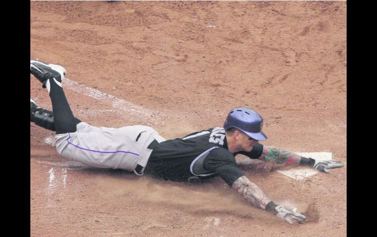 Brandon Barnes llega barrido al home plate luego de batear su jonrón dentro del parque y anotar la carrera de la victoria para Colorado AP /